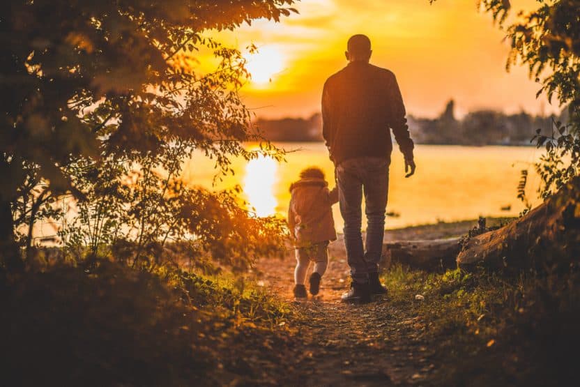 Photo of a father and son hiking by a lake.
